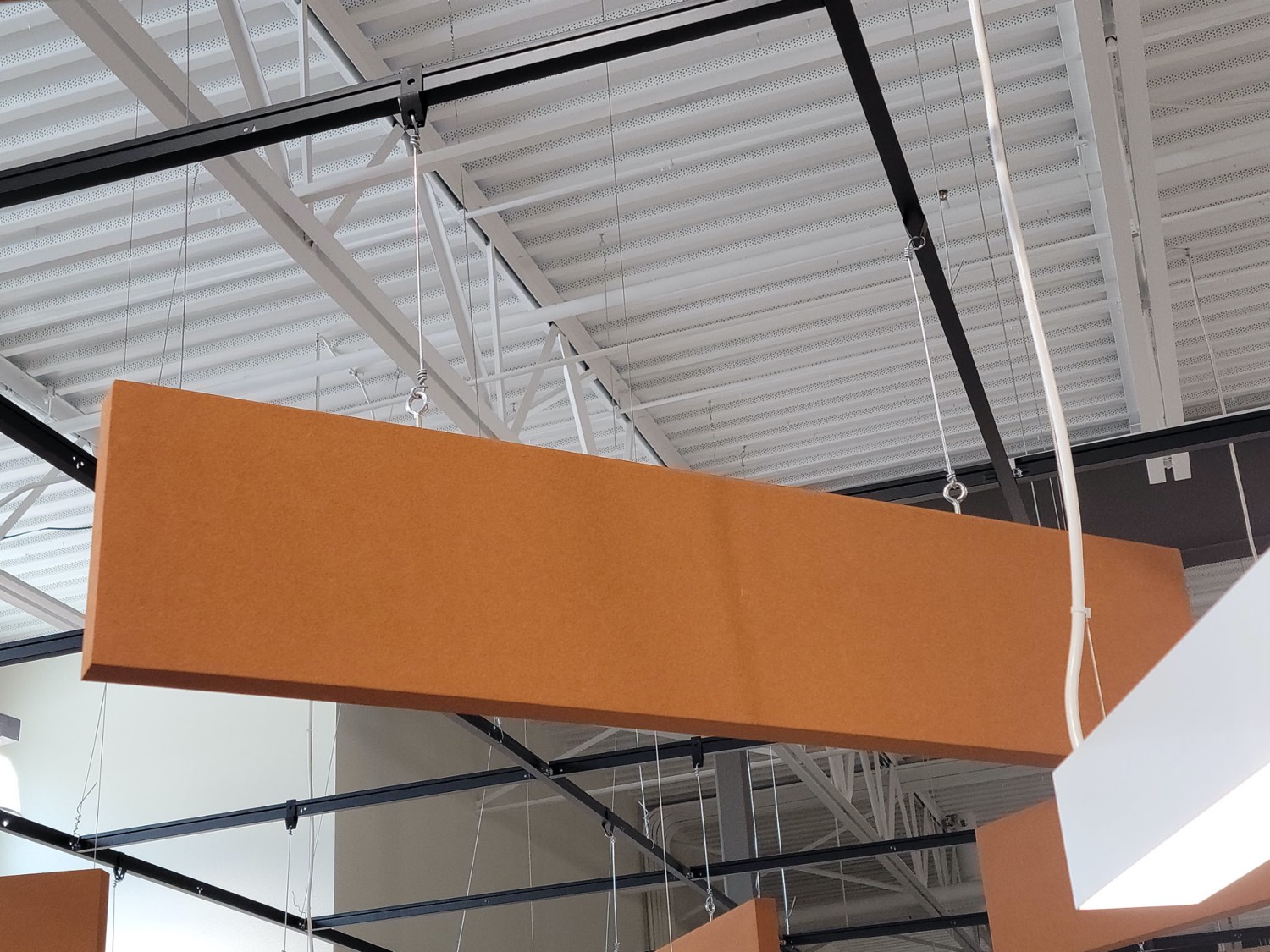 Orange acoustic cloud baffle suspended in a commercial space by Skampy Acoustical