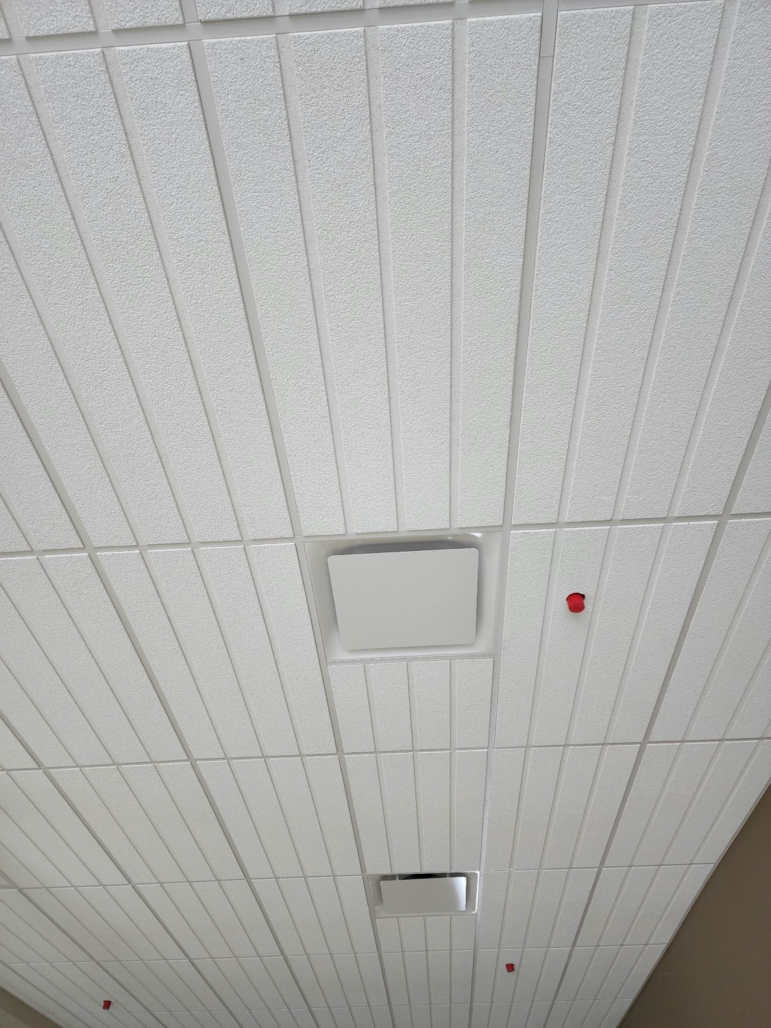 White linear metal suspended ceiling installed by Skampy Acoustical