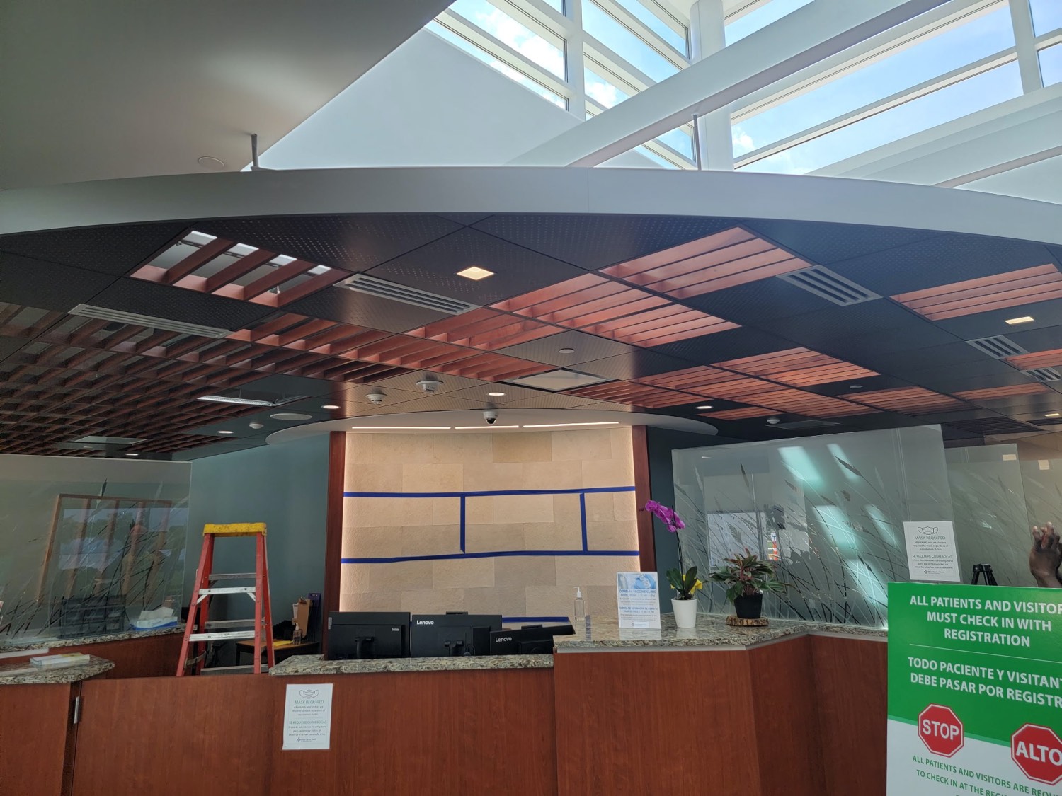 Curved wood-slat and perforated metal feature ceiling in a medical lobby by Skampy Acoustical